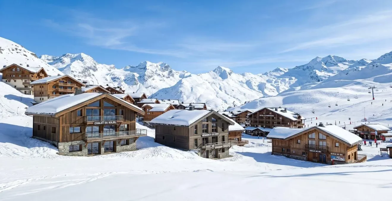 Chalet contemporain en bois avec grandes baies vitrées dans un paysage enneigé de montagne sous un ciel bleu d'hiver