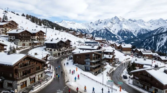 Vue panoramique d'un village de Courchevel montrant des chalets savoyards à différents niveaux d'altitude avec sommets alpins enneigés en arrière-plan